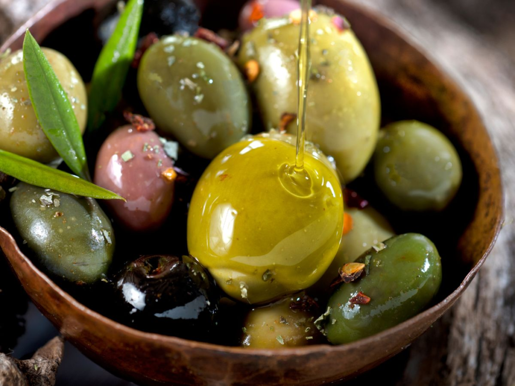 A bowl of olives with a variety of colors and shapes